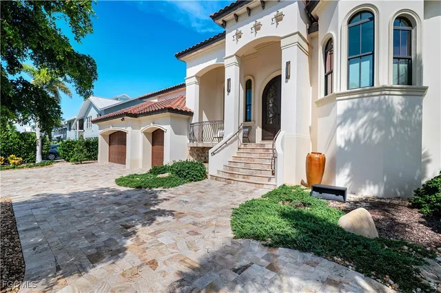 a view of a house with a yard plants and large tree