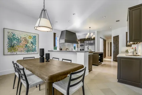 a kitchen with stainless steel appliances granite countertop a kitchen island a stove a table and a sink