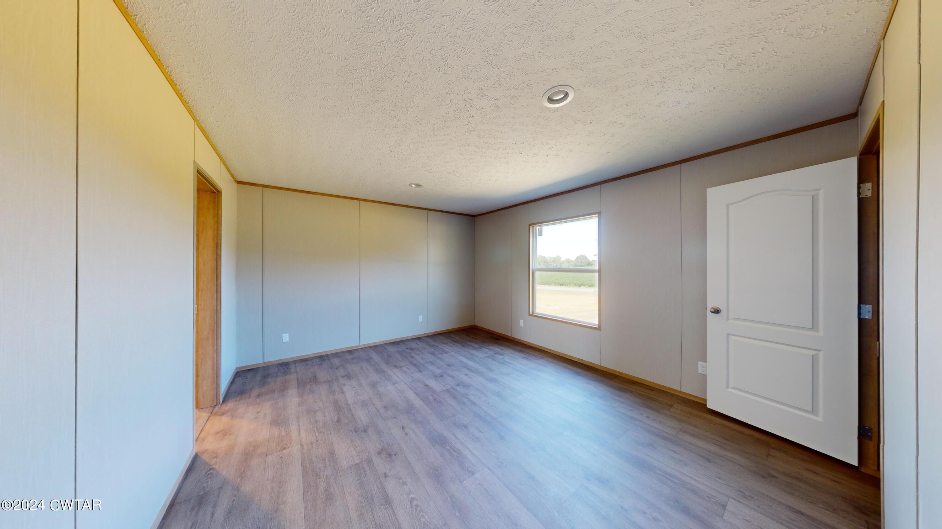 463 Peckerwood Point Road Newbern, TN 38059 - Photo 14 of 35 an empty room with wooden floor and windows