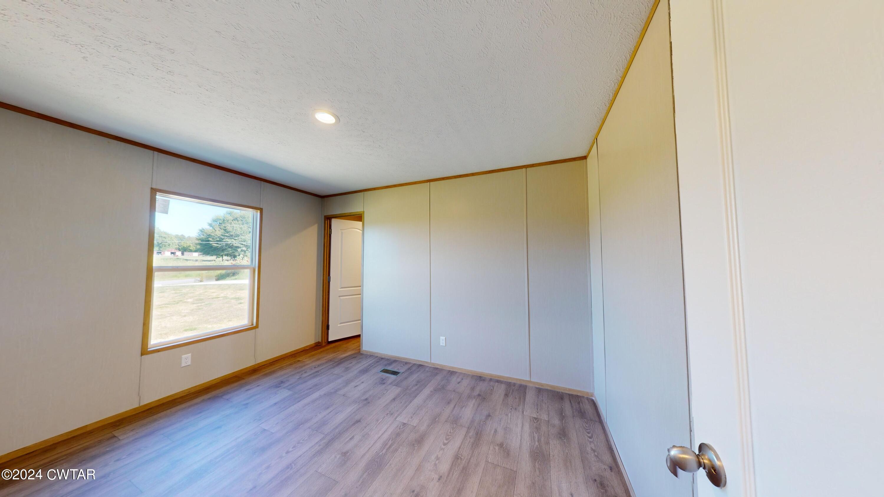 463 Peckerwood Point Road Newbern, TN 38059 - Photo 25 of 35 an empty room with wooden floor and windows