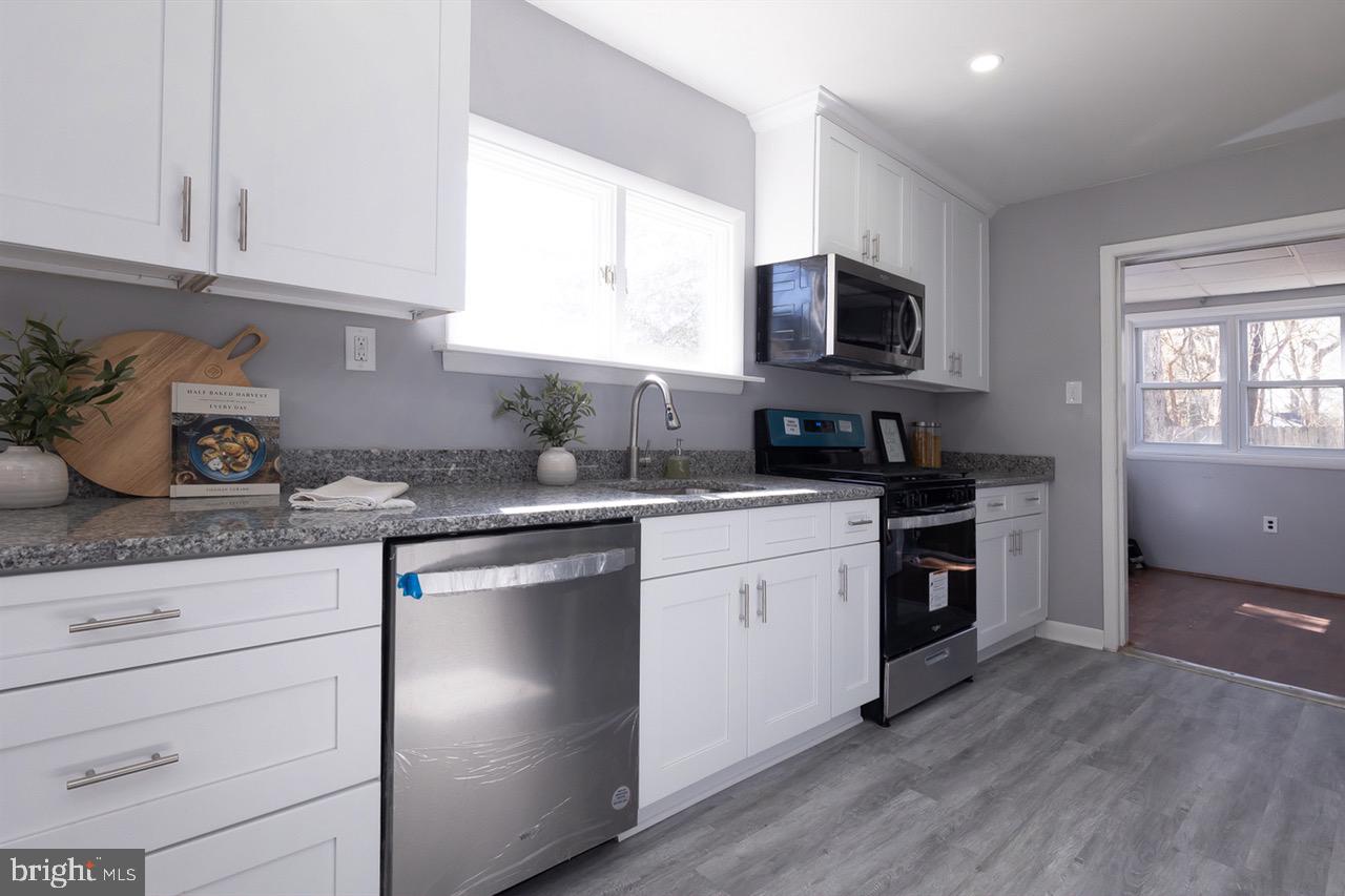 112 East 7th Avenue Pine Hill, NJ 08021 - Photo 3 of 27 a kitchen with stainless steel appliances granite countertop a sink a stove and a granite counter tops with wooden floors