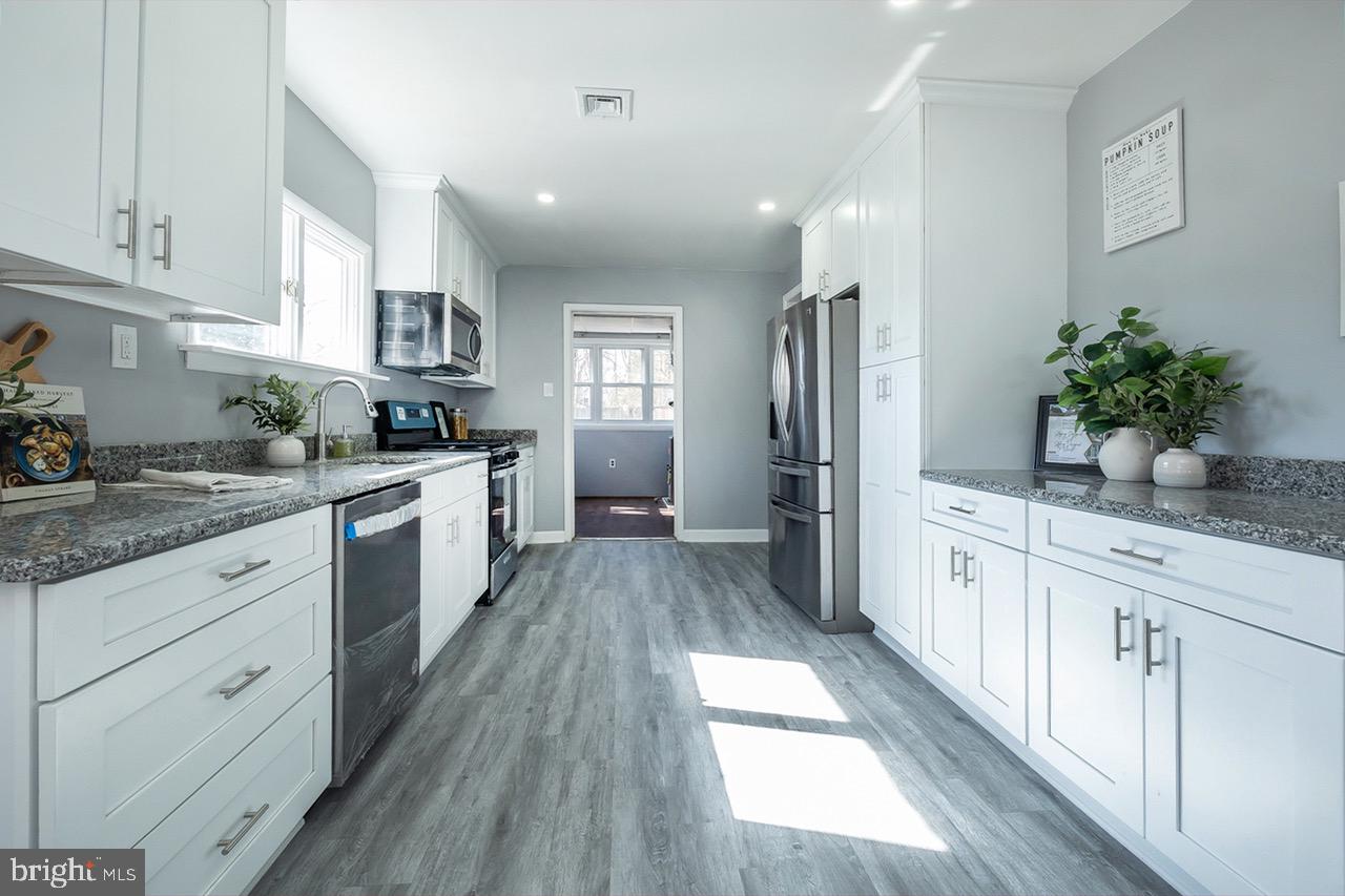 112 East 7th Avenue Pine Hill, NJ 08021 - Photo 4 of 27 a kitchen with granite countertop a refrigerator a sink dishwasher stove and white cabinets with wooden floor