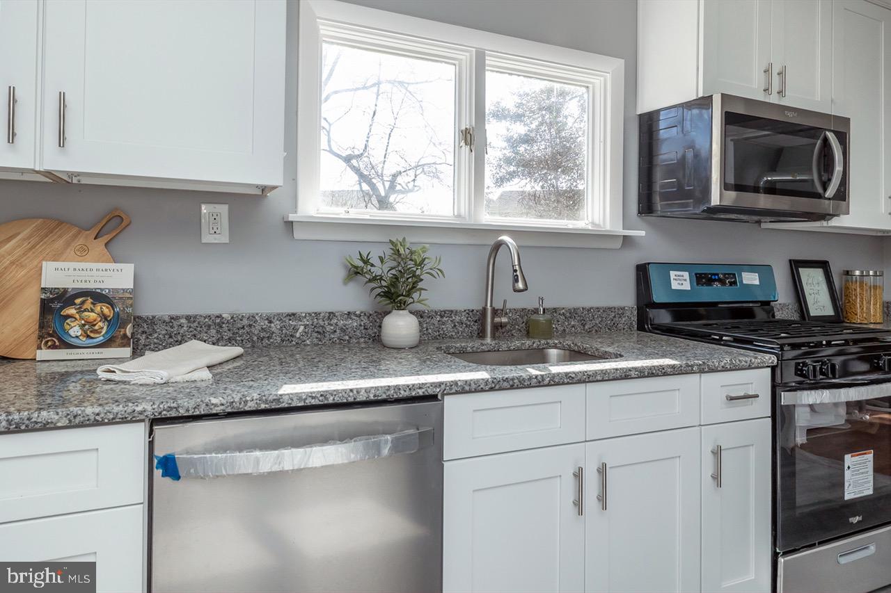 112 East 7th Avenue Pine Hill, NJ 08021 - Photo 5 of 27 a kitchen with granite countertop stainless steel appliances a sink a stove cabinets and a window