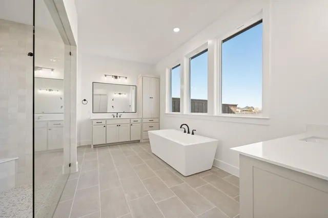 a spacious bathroom with a double vanity sink mirror and bathtub