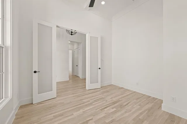 a view of an empty room with wooden floor and a bathroom