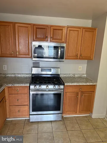 a kitchen with granite countertop a stove top oven microwave and cabinets