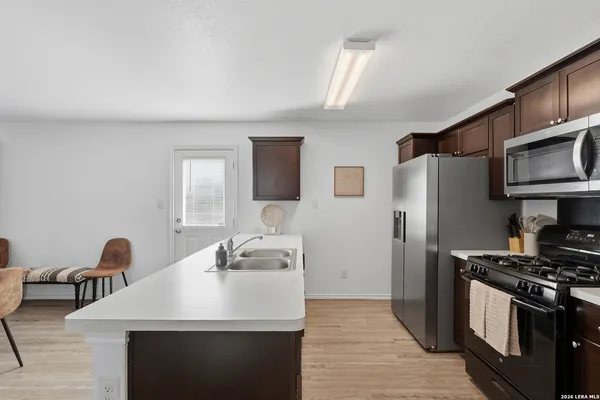 a kitchen with stainless steel appliances a sink a stove a refrigerator cabinets and furniture