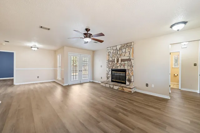 an empty room with windows fireplace and a ceiling fan