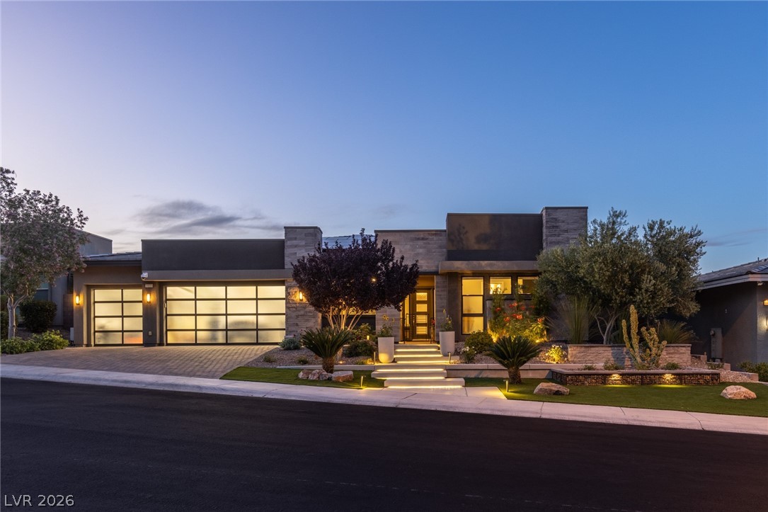 10118 Copper Edge Road Las Vegas, NV 89148 - Photo 1 of 48 An illuminated modern facade beckons with sleek stone and stucco finishes under a twilight sky.