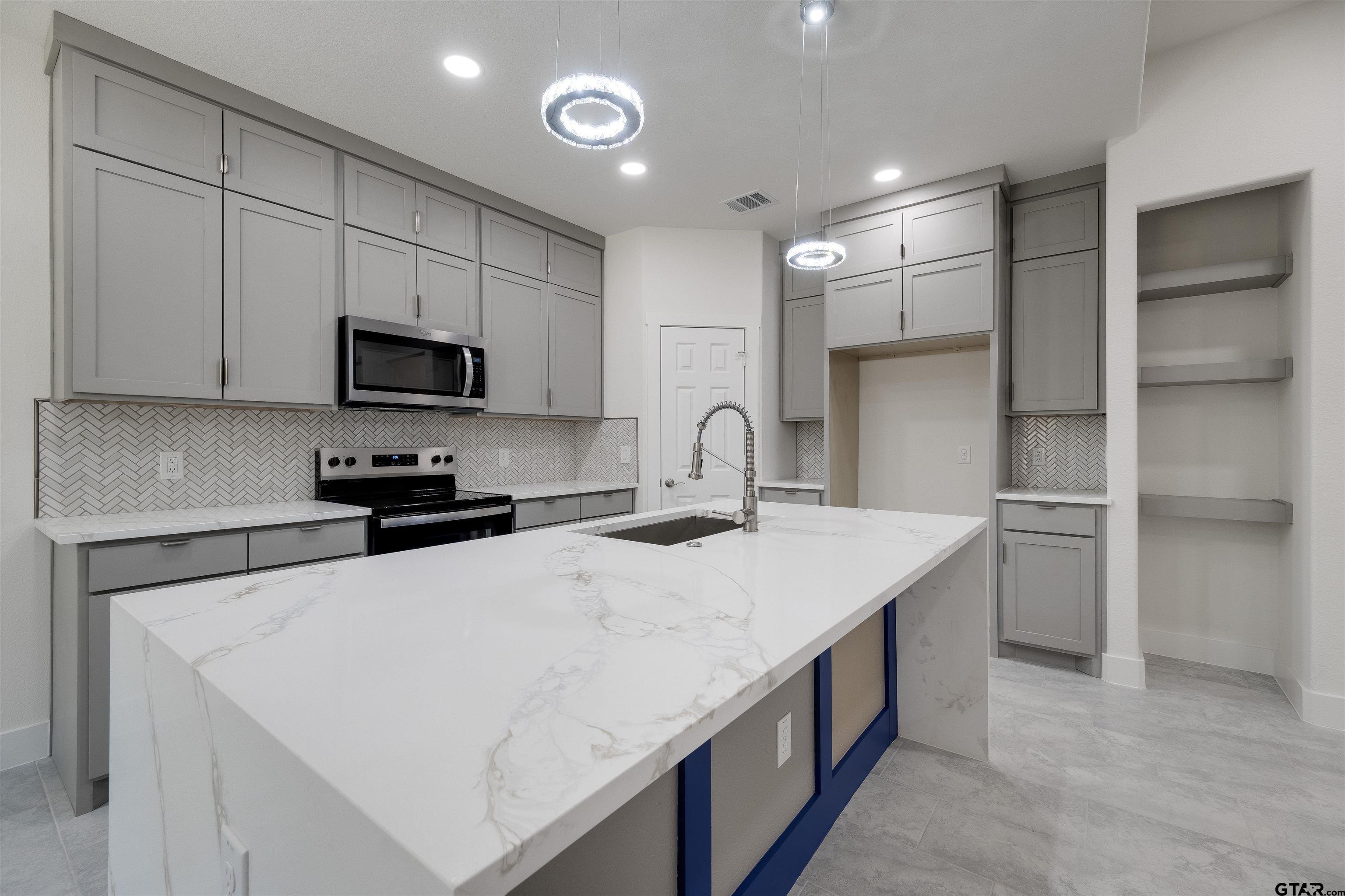 201 Victory Street Palestine, TX 75803 - Photo 12 of 37 a kitchen with kitchen island a sink stainless steel appliances and cabinets