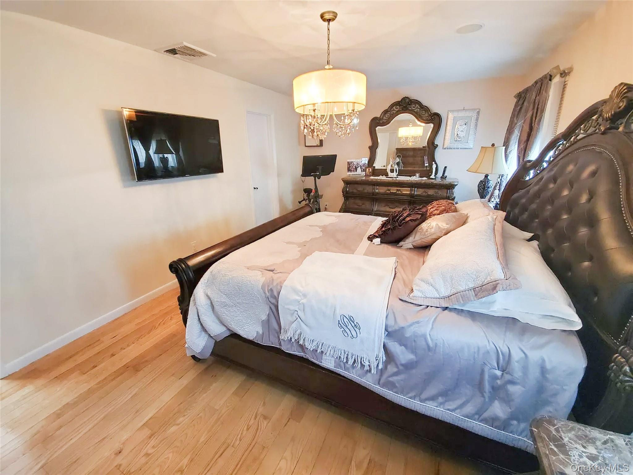 66 Leroy Avenue Valhalla, NY 10595 - Photo 17 of 31 a bedroom with a bed mirror on dresser and a chandelier