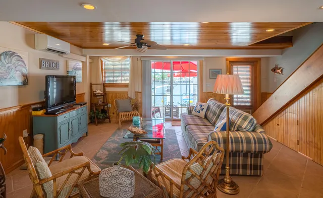 a living room with furniture a flat screen tv and floor to ceiling window