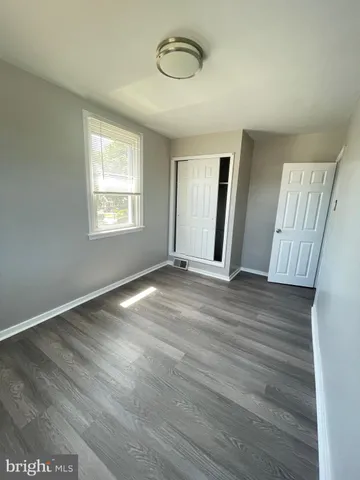 a view of an empty room with wooden floor and window