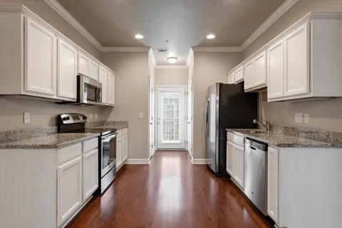 a kitchen with stainless steel appliances granite countertop a refrigerator a stove top oven a sink dishwasher and wooden cabinets with wooden floor