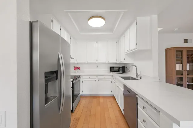 a kitchen with a refrigerator a sink and white cabinets