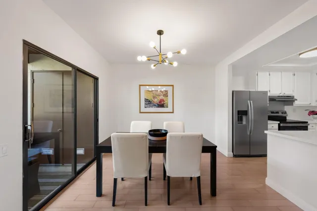 a dining room with wooden floor a chandelier a wooden table and chairs