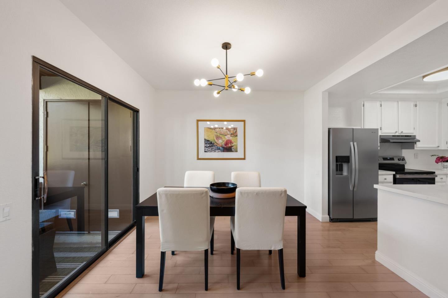 473 Costa Mesa Terrace, Unit C Sunnyvale, CA 94085 - Photo 6 of 40 a dining room with wooden floor a chandelier a wooden table and chairs
