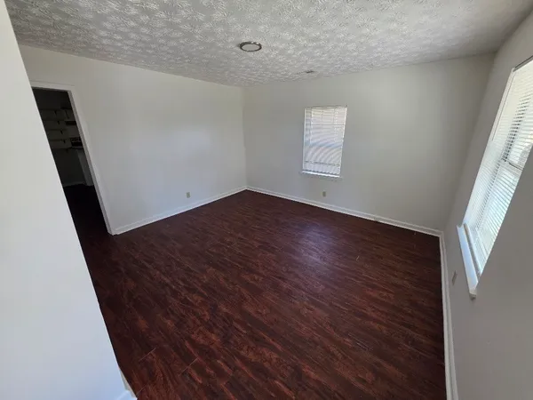 an empty room with wooden floor and windows
