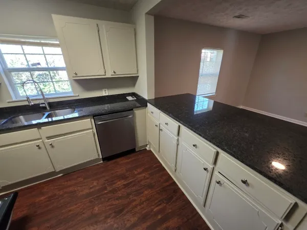 a kitchen with granite countertop white cabinets and a wooden floor