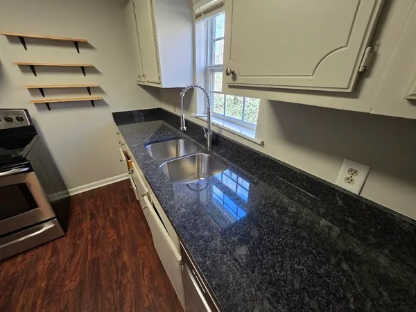 a kitchen with kitchen island granite countertop a sink stove and cabinets