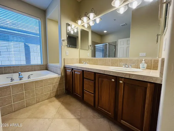 a spacious bathroom with a double vanity sink mirror and bathtub