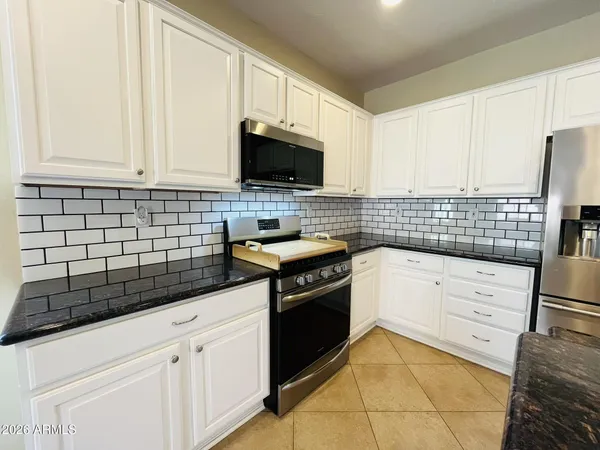 a kitchen with granite countertop white cabinets and stainless steel appliances