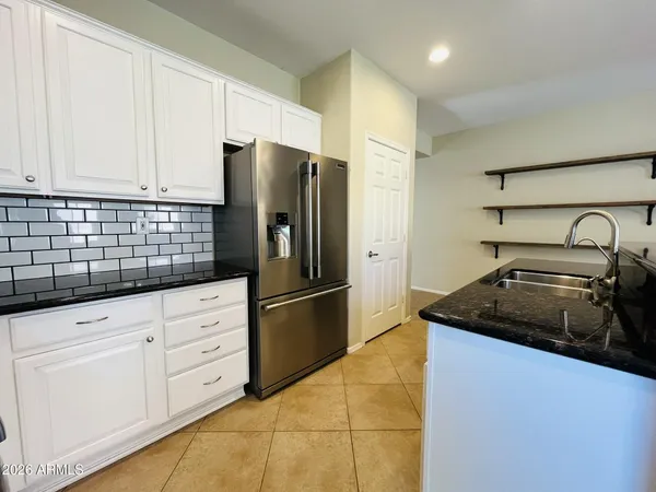a kitchen with granite countertop white cabinets and refrigerator