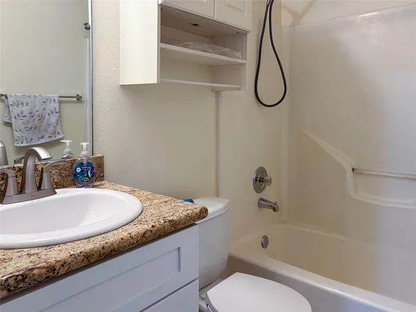 a bathroom with a granite countertop sink a toilet and bathtub