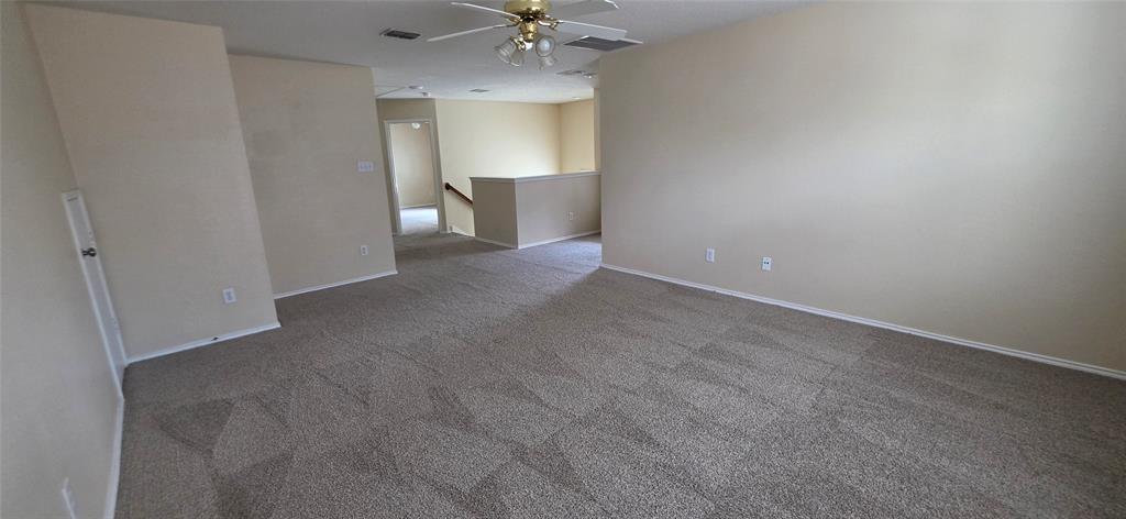 2820 Deer Ridge Drive Rockwall, TX 75032 - Photo 18 of 36 Expansive carpeted floor with a geometric pattern, neutral wall tones, and a ceiling fan with integrated lighting