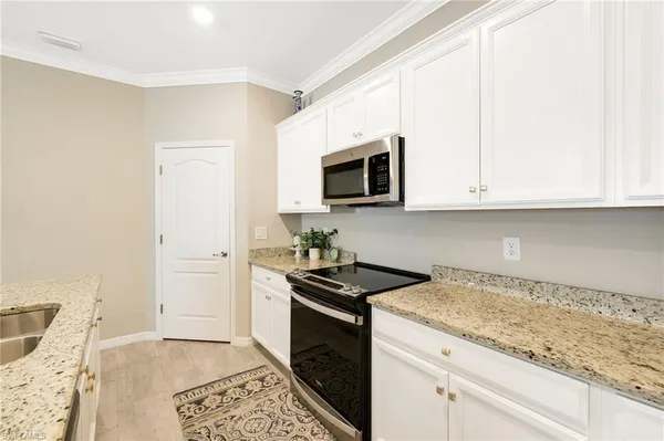 a kitchen with granite countertop white cabinets and stainless steel appliances