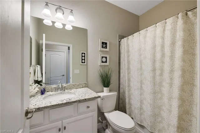 a bathroom with a granite countertop sink a toilet and a mirror