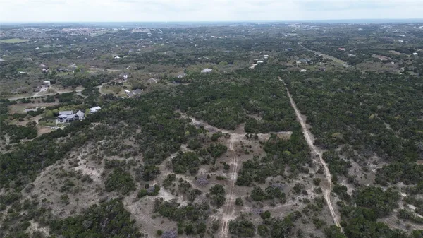 a view of a dry yard with trees in the background