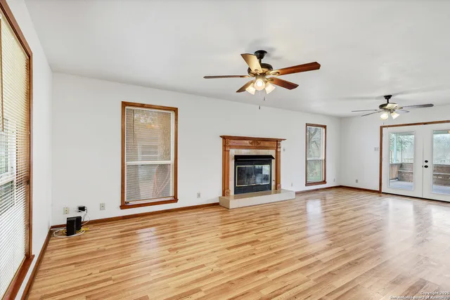 an empty room with wooden floor fireplace and windows