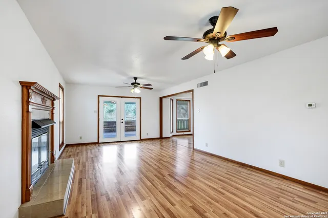 a view of empty room with wooden floor and fan