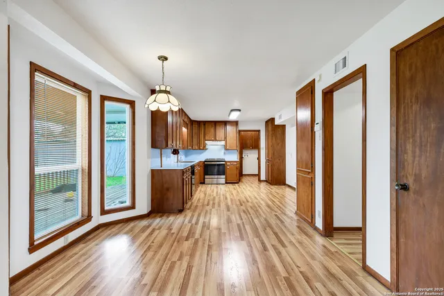 a view of a living room and kitchen with furniture wooden floor windows