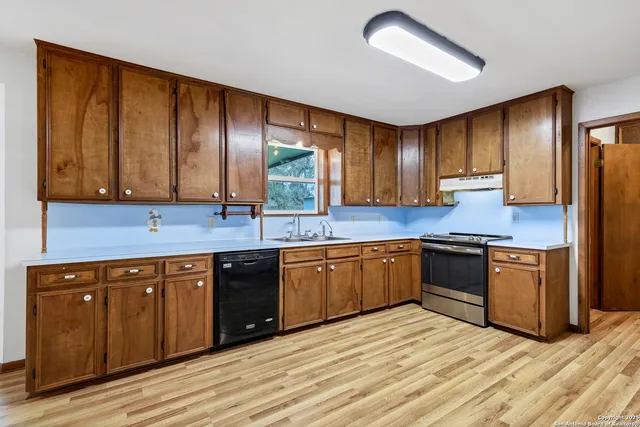 a kitchen with stainless steel appliances granite countertop a sink a stove cabinets and wooden floor