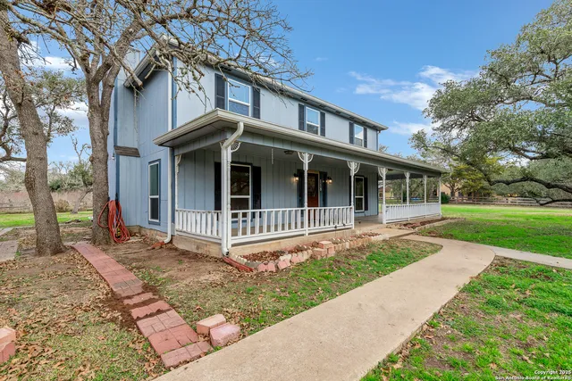 a view of a house with a yard and large tree