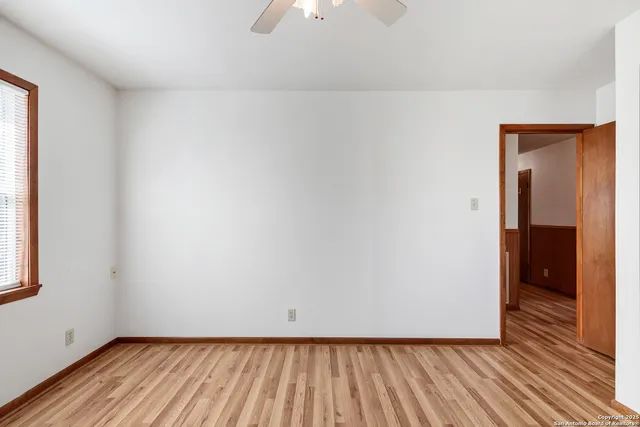 a view of an empty room with wooden floor and closet