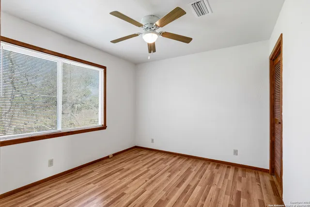 an empty room with wooden floor and windows