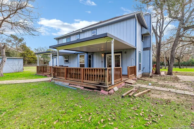 a view of a house with a yard and deck area under a large tree