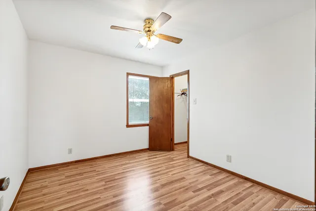 an empty room with wooden floor and fan