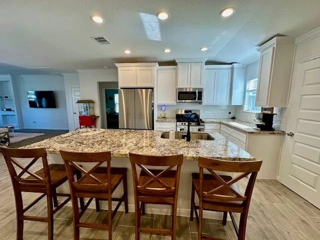 a kitchen with stainless steel appliances granite countertop a table chairs sink refrigerator and microwave