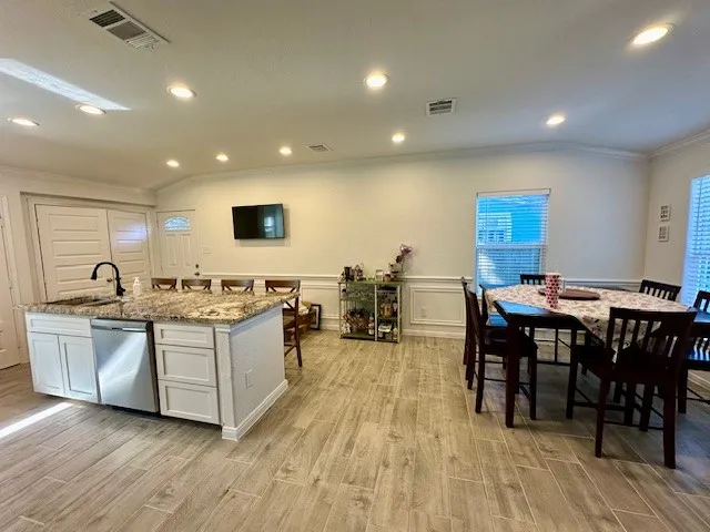 a living room with stainless steel appliances granite countertop a table chairs and a microwave