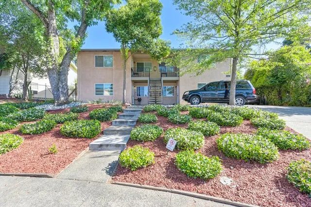 a front view of a house with a yard and potted plants