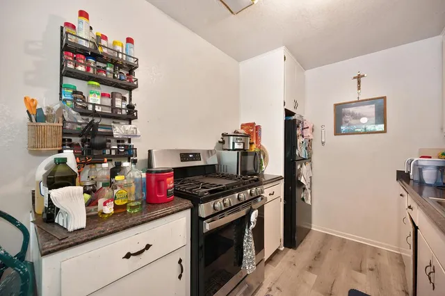 a kitchen with stainless steel appliances granite countertop a stove and a view of living room