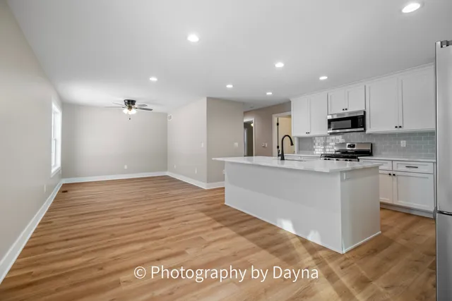 a kitchen with stainless steel appliances granite countertop a sink a stove top oven and wooden floor