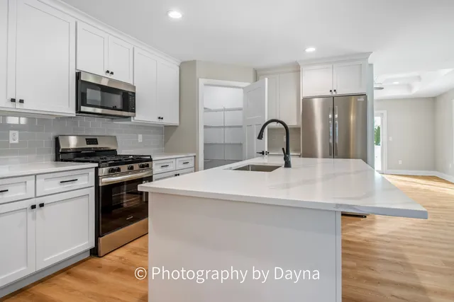 a large kitchen with kitchen island a sink a counter top space stainless steel appliances and cabinets