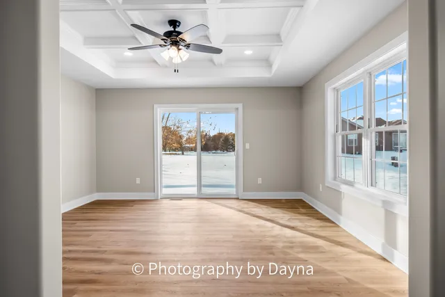 an empty room with chandelier fan and windows