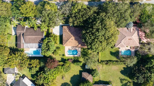 an aerial view of a house with a yard and large trees