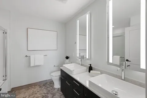 a bathroom with a double vanity sink toilet and a mirror